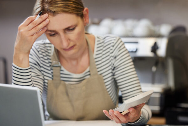 Image shows a business owner trying to work out how to manage business debt.