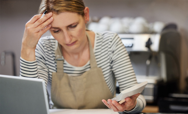 Image shows a business owner trying to work out how to manage business debt.