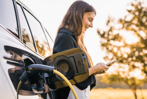 Business owner with her EV to illustrate whether a business owner should buy an EV