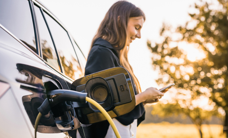 Business owner with her EV to illustrate whether a business owner should buy an EV